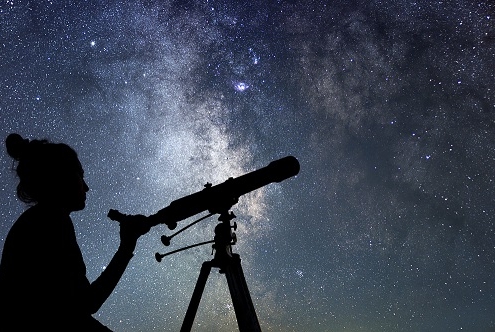 A woman with a telescope stargazing