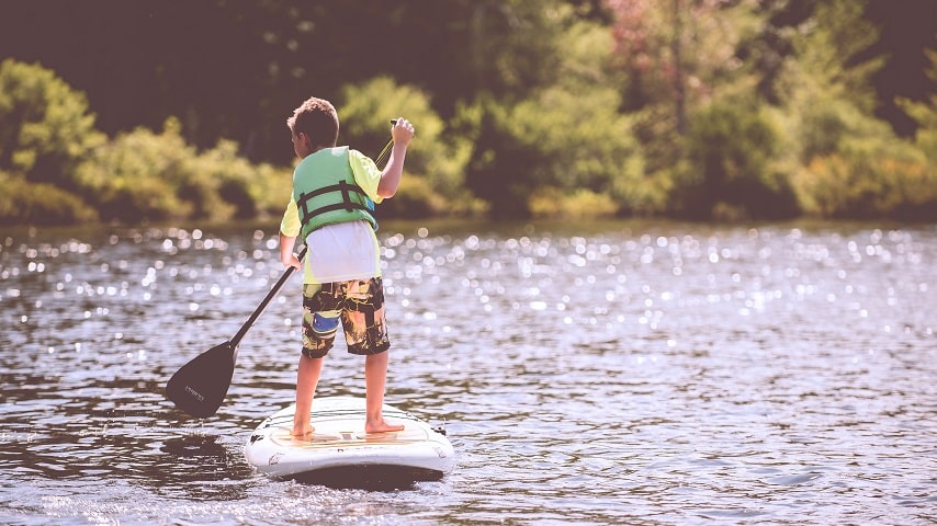 boy paddleboarding in the summer