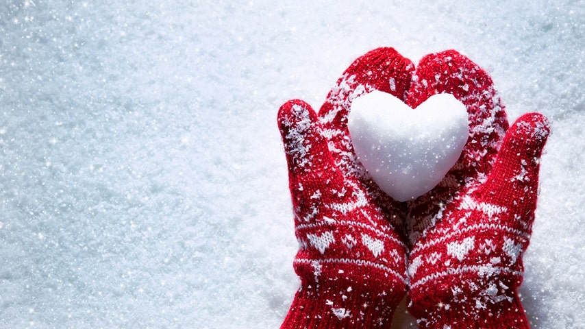 Christmas mittens holding snow heart